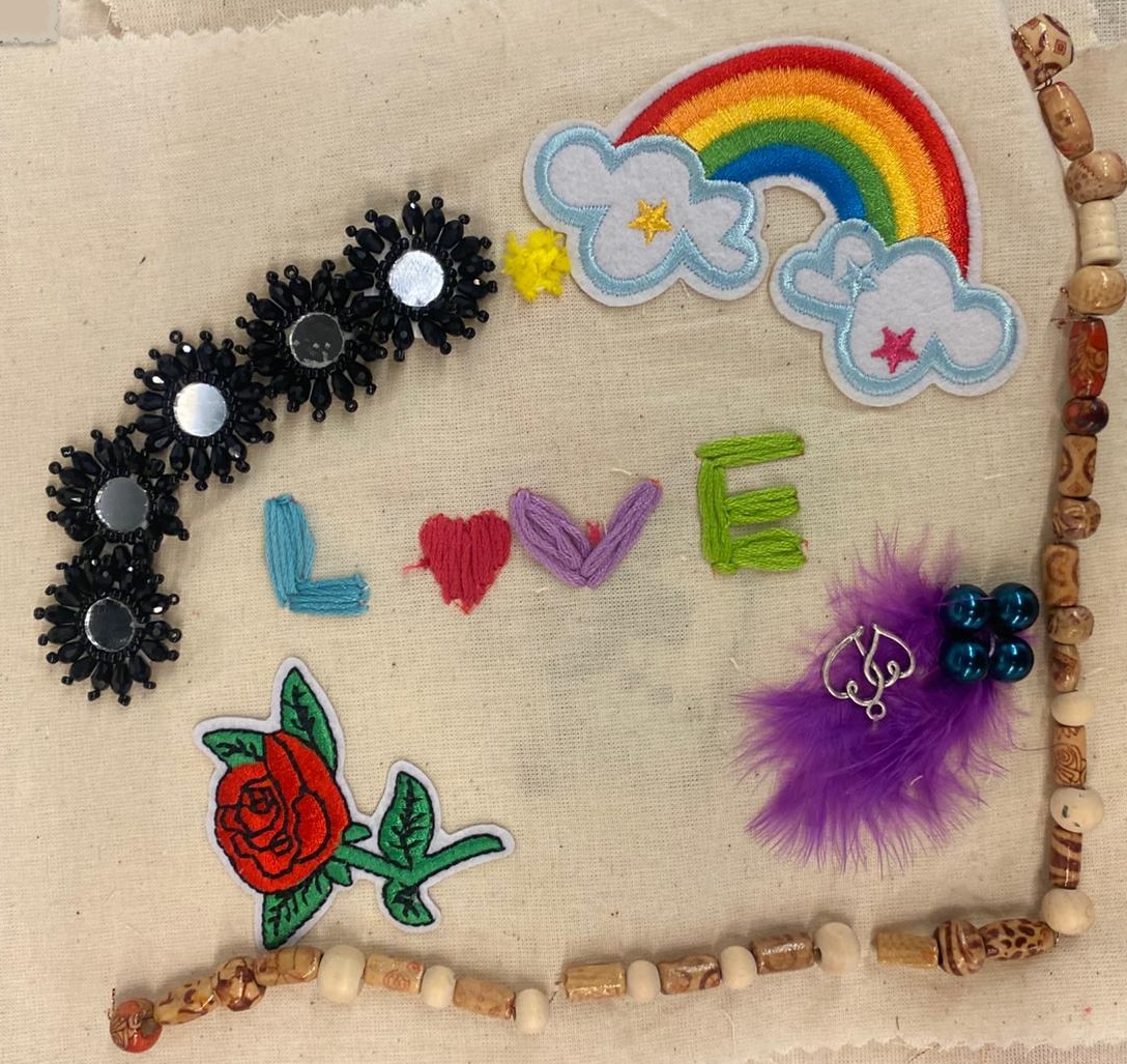 Pride Heart Colourful embroidery including the word 'love', a rainbow, a redvrose, a purple feature and some beads